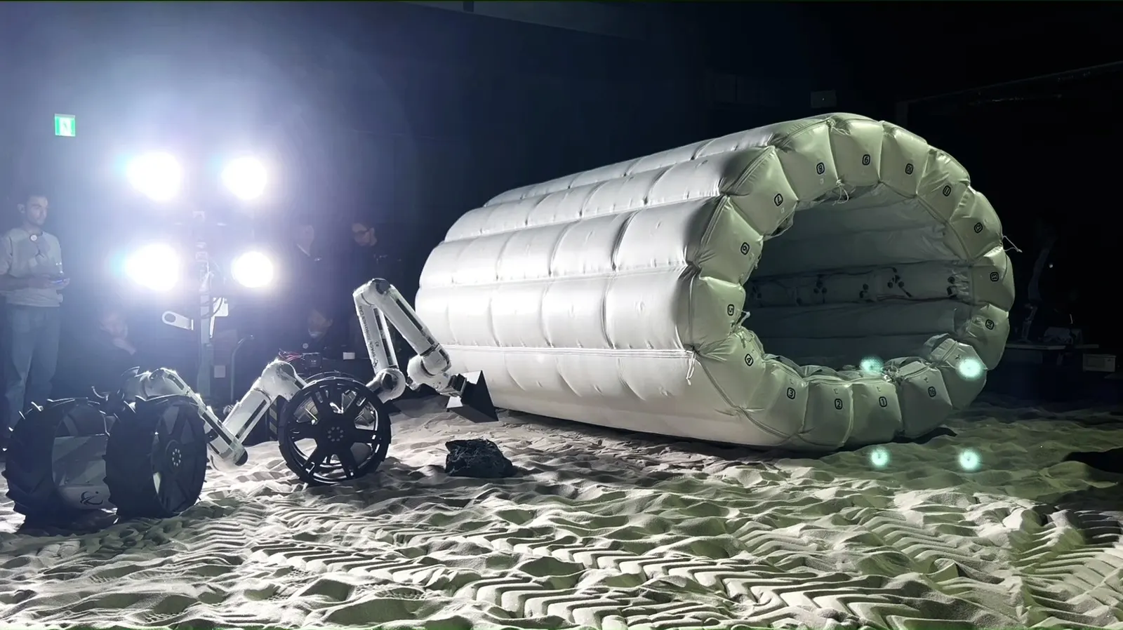 A MoonBot Dragon monitoring the HIDAS inflatable habitat module as it inflates, using a camera on its limb, JAXA Space Exploration Test Field.