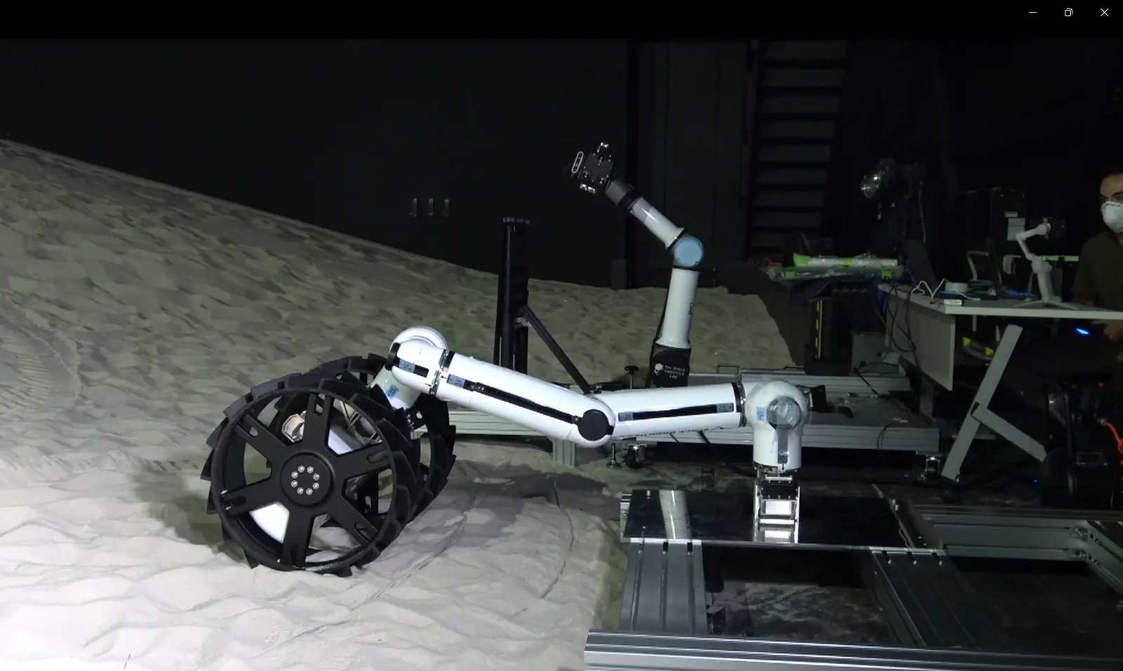 A limb lifting a wheel off the launch-lock palette to form a Minimal robot.