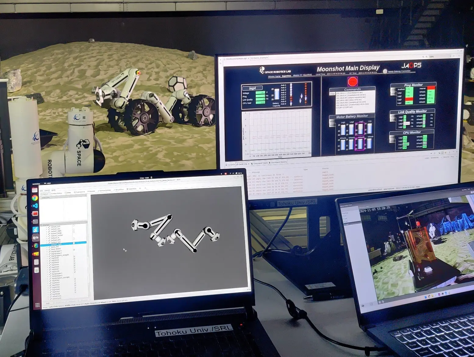 Mission control at the JAXA Space Exploration Test Field: the operator desk, with a MoonBot Dragon on the sand behind the screens.